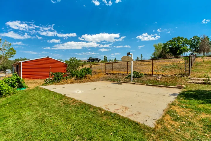 Concrete pad with a portable basketball hoop, bordered by a chain-link fence