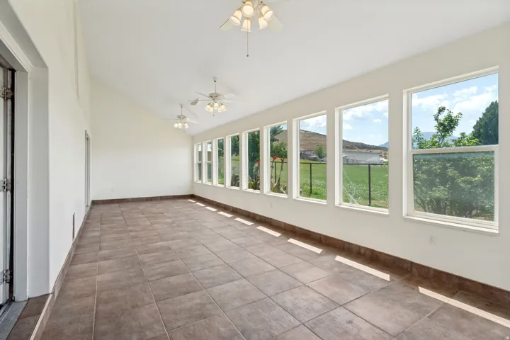 Spacious sunroom featuring extensive window-line, vaulted ceiling, and durable tile flooring
