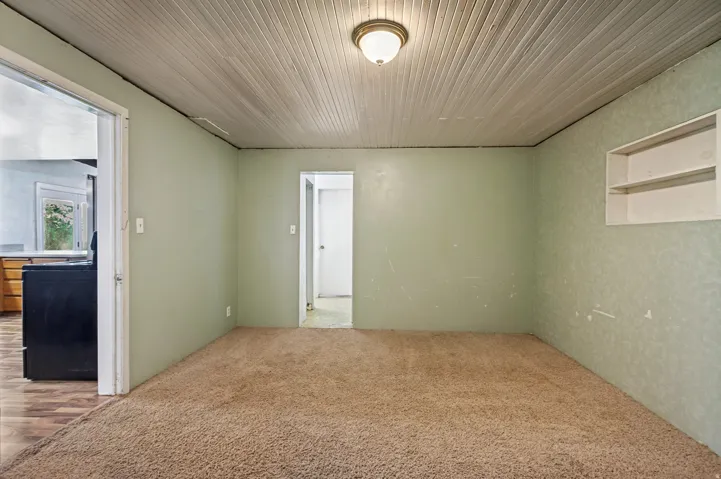 Carpeted room featuring a plank ceiling, recessed shelving, and a semi-flush mount light fixture