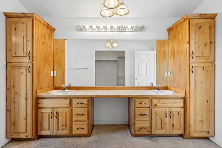 Dual vanity with integrated sinks, ample countertop space, and extensive built-in wood cabinetry for storage