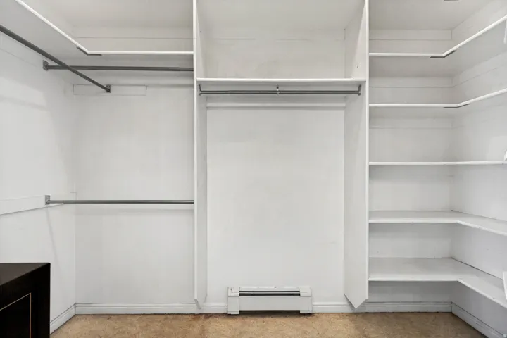 Expansive closet featuring integrated shelving, multiple hanging rods, corner storage, and a baseboard heater