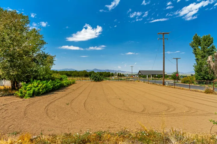 Cleared land parcel featuring tilled earth, mature trees, and partial perimeter fencing
