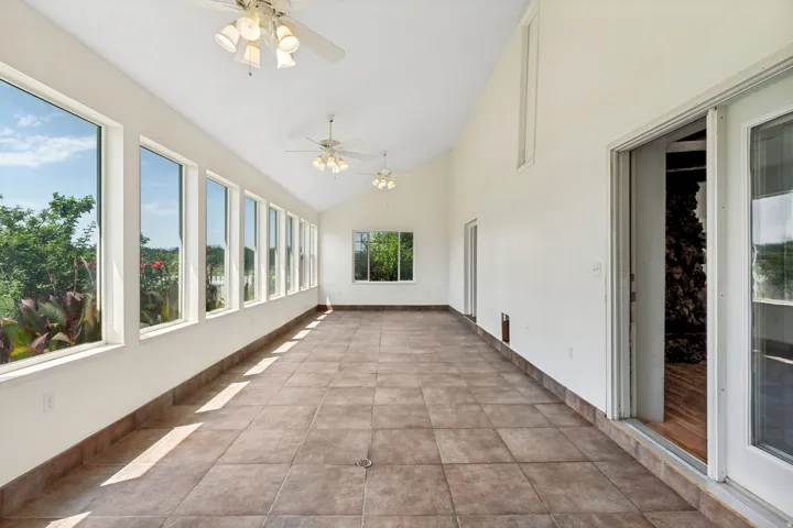 Expansive sunroom featuring a vaulted ceiling and multiple ceiling fans