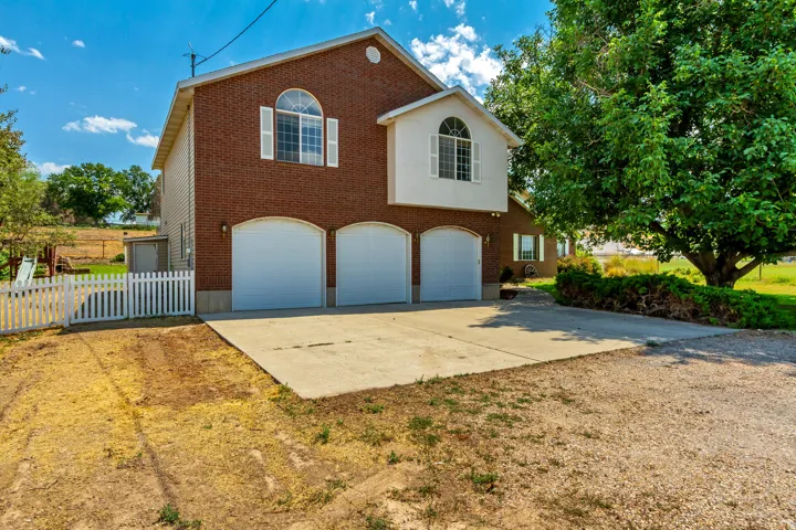 Brick and siding exterior featuring a three-car garage with arched doors