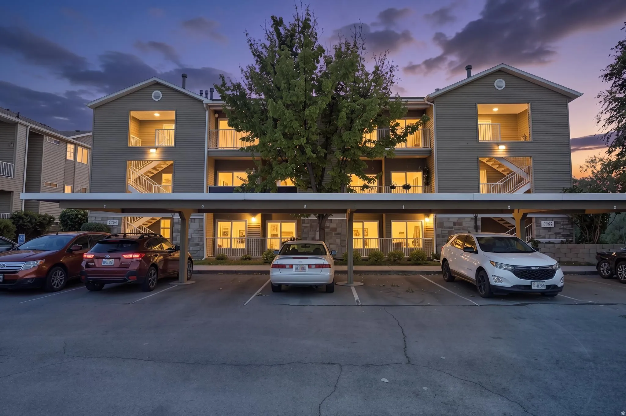 Multi-story residential building featuring balconies, exterior staircases, and ground-level patios