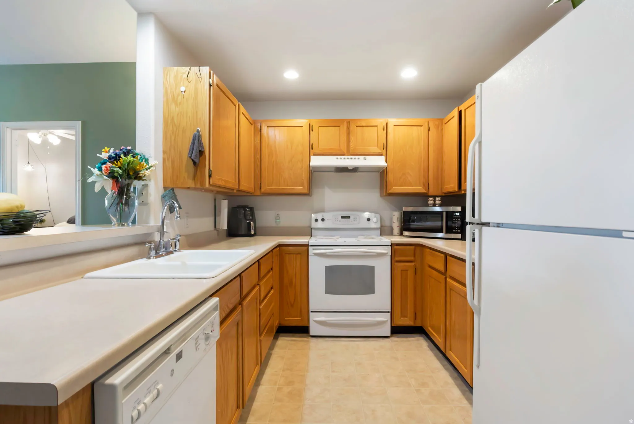 U-shaped kitchen featuring wood-finish cabinetry, light-toned countertops, and a double basin sink