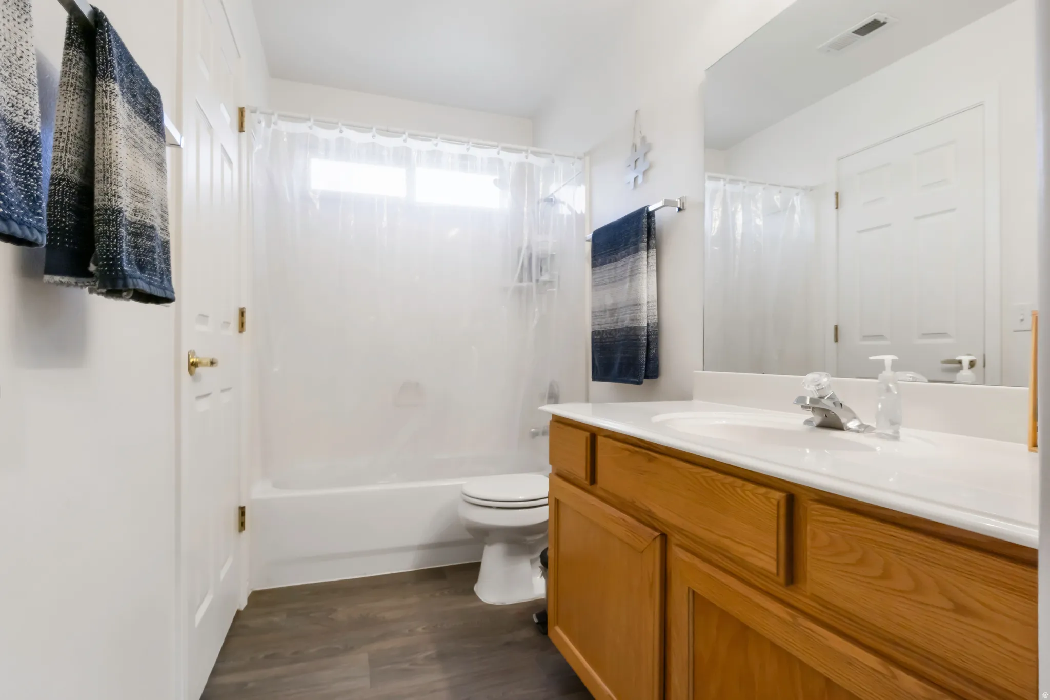 Bathroom featuring a wood-finish vanity with an integrated sink and mirror, a tub/shower combination, and wood-finish flooring