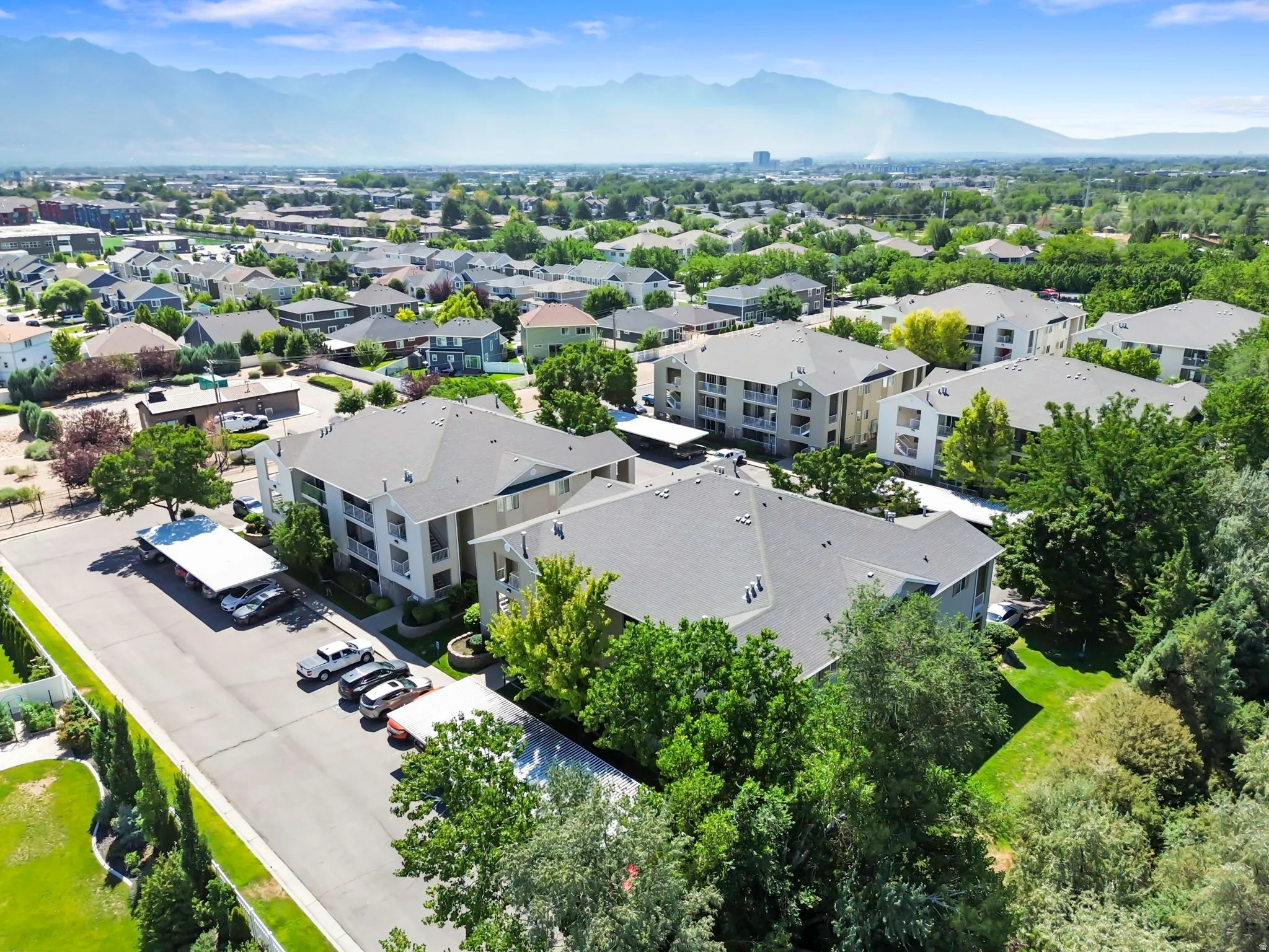 Residential complex featuring multiple buildings with private balconies, surrounded by mature trees and manicured green spaces