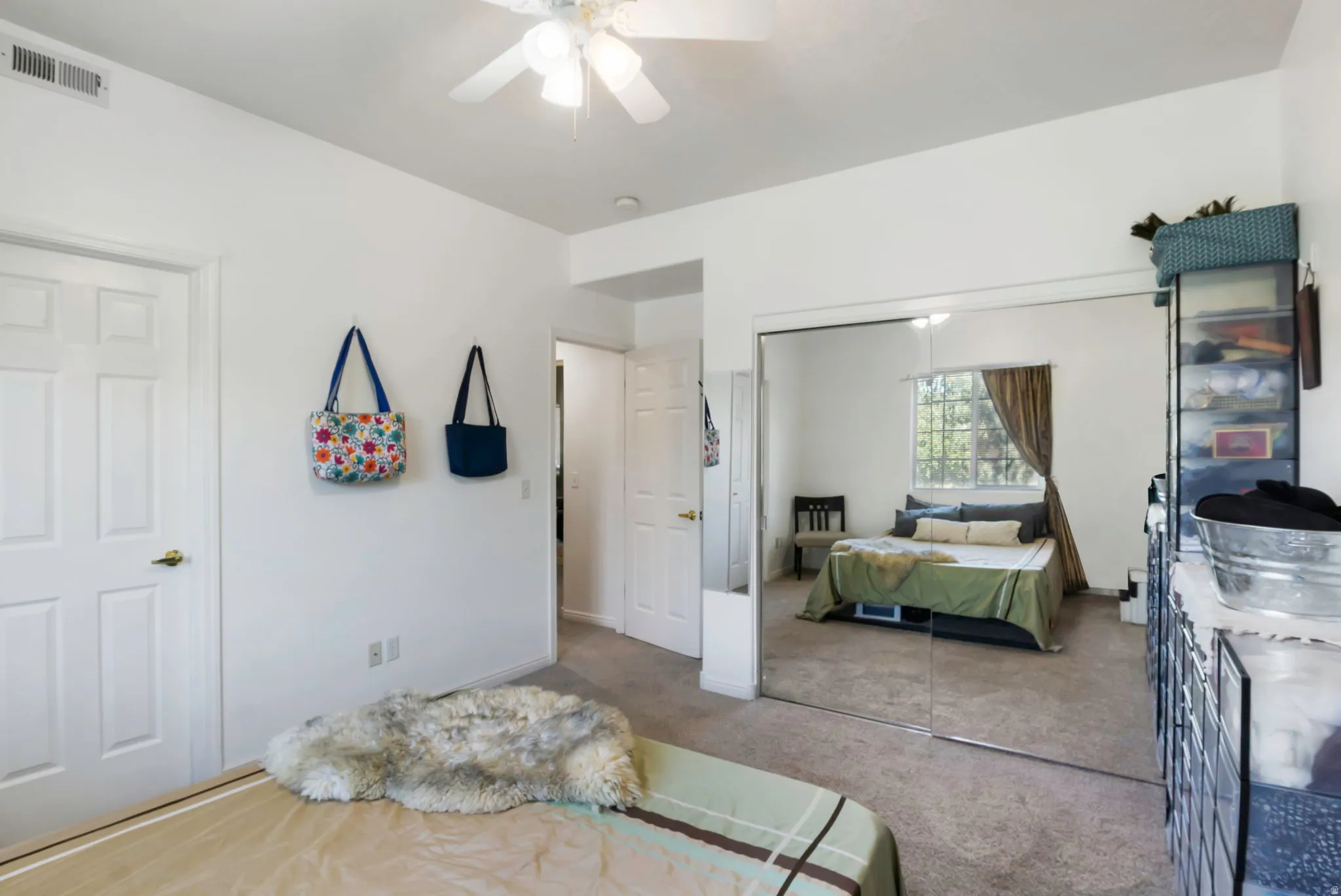Ceiling fan with integrated lighting, mirrored closet doors, paneled interior doors, and neutral carpeting