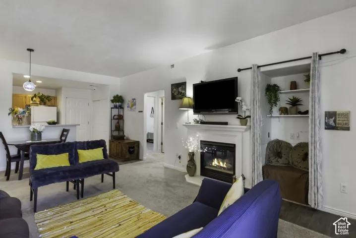 Living area featuring a fireplace with a white mantel, built-in shelving, carpeted flooring, and a dining area with a breakfast bar