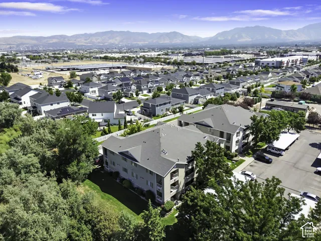 Multistory residential building with balconies, surrounded by mature trees and paved parking areas