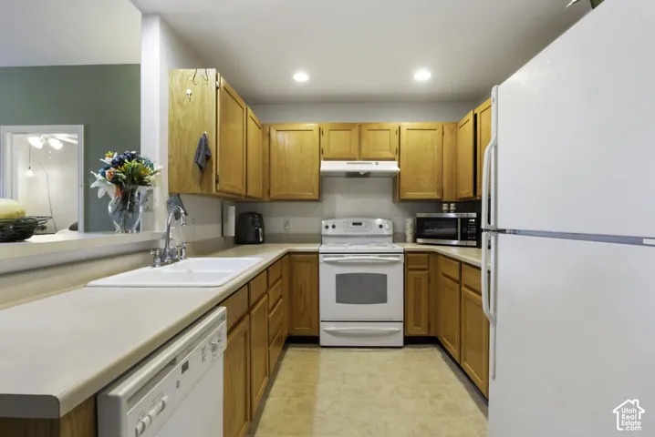 U-shaped kitchen featuring wood-finish cabinetry, light-toned countertops, and a double basin sink