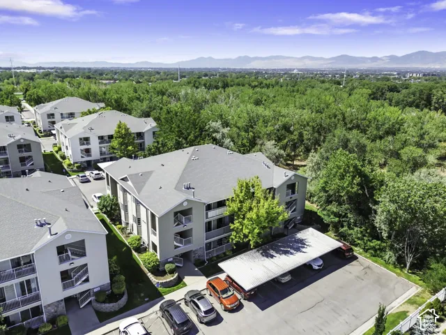 Multi-story buildings featuring balconies, a covered parking structure, and surrounding landscaped grounds
