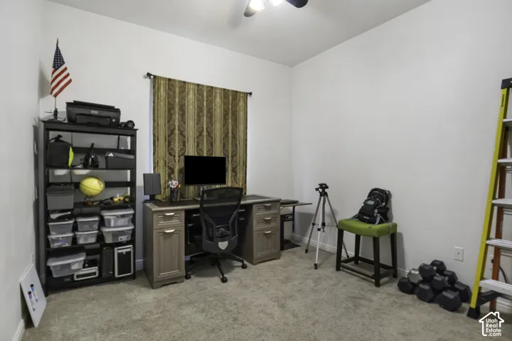 Carpeted room with a ceiling fan, window featuring patterned drapes, and neutral wall paint