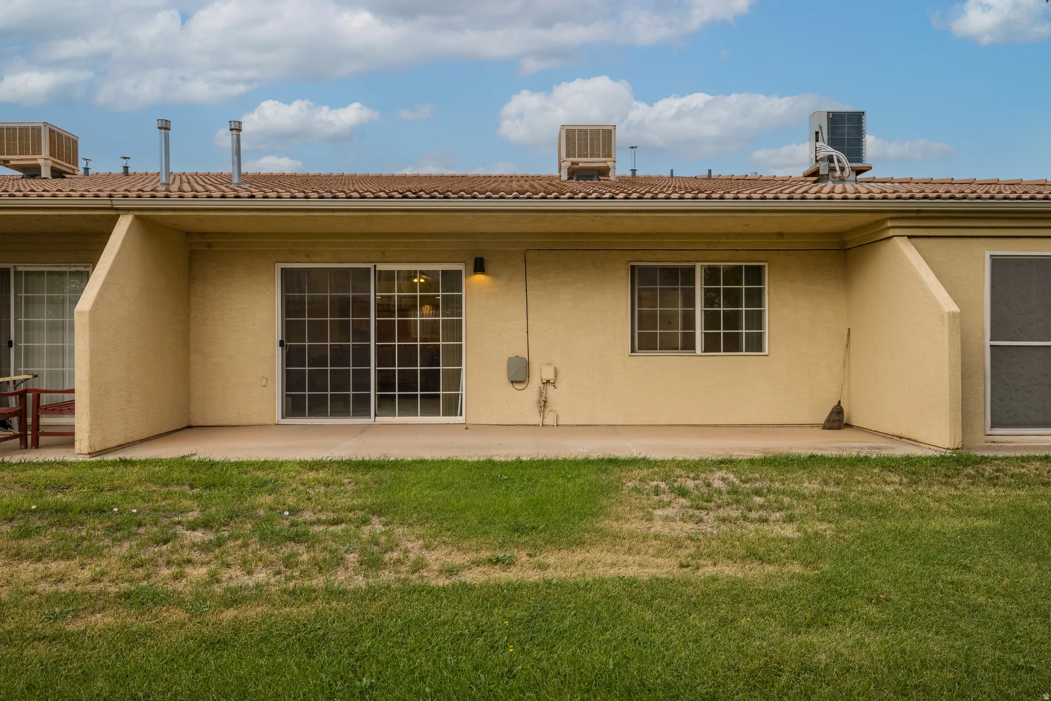 Rear patio with sliding glass doors, tile roof, and stucco exterior