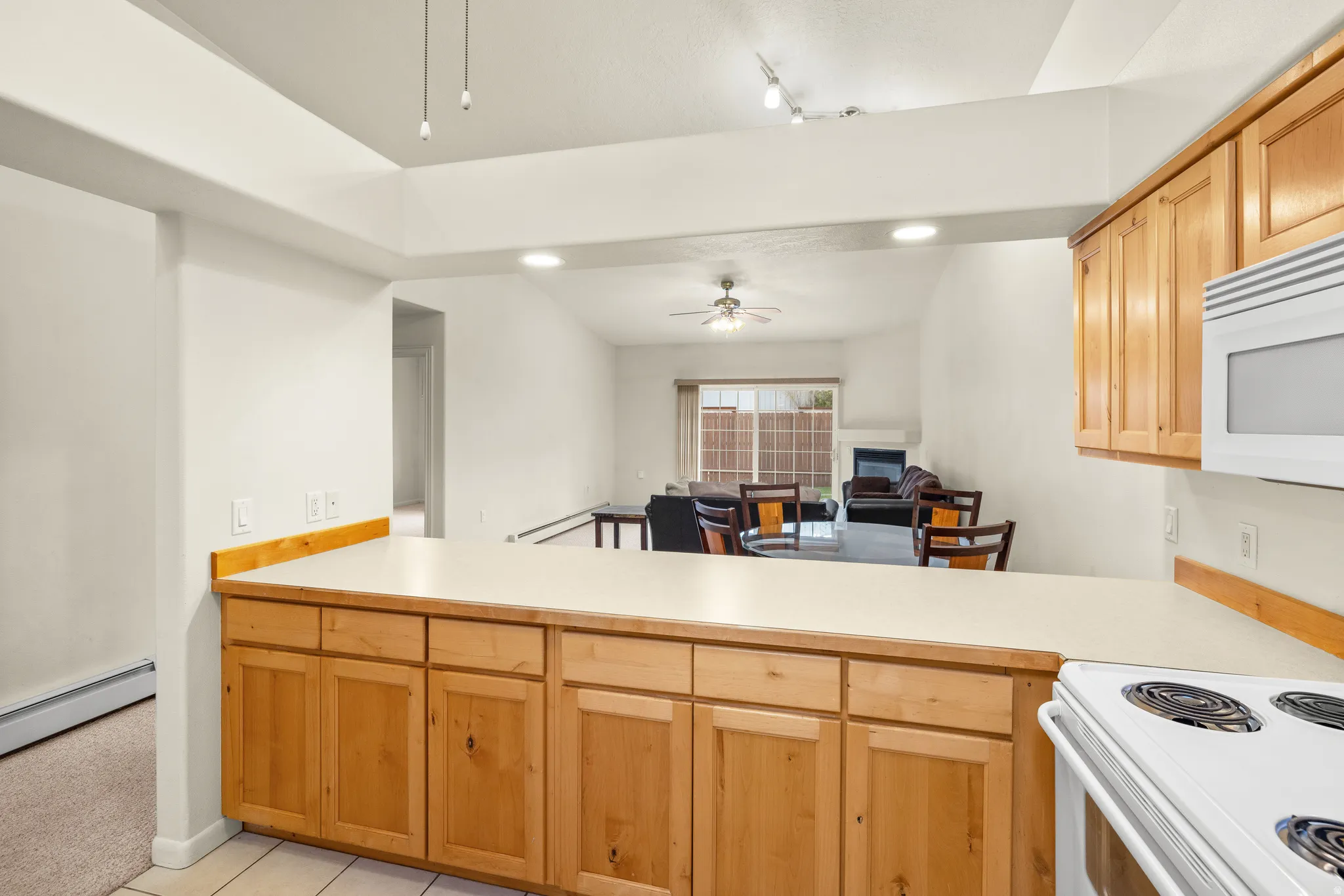 Kitchen with wood-finish cabinetry, solid surface countertops, and white appliances
