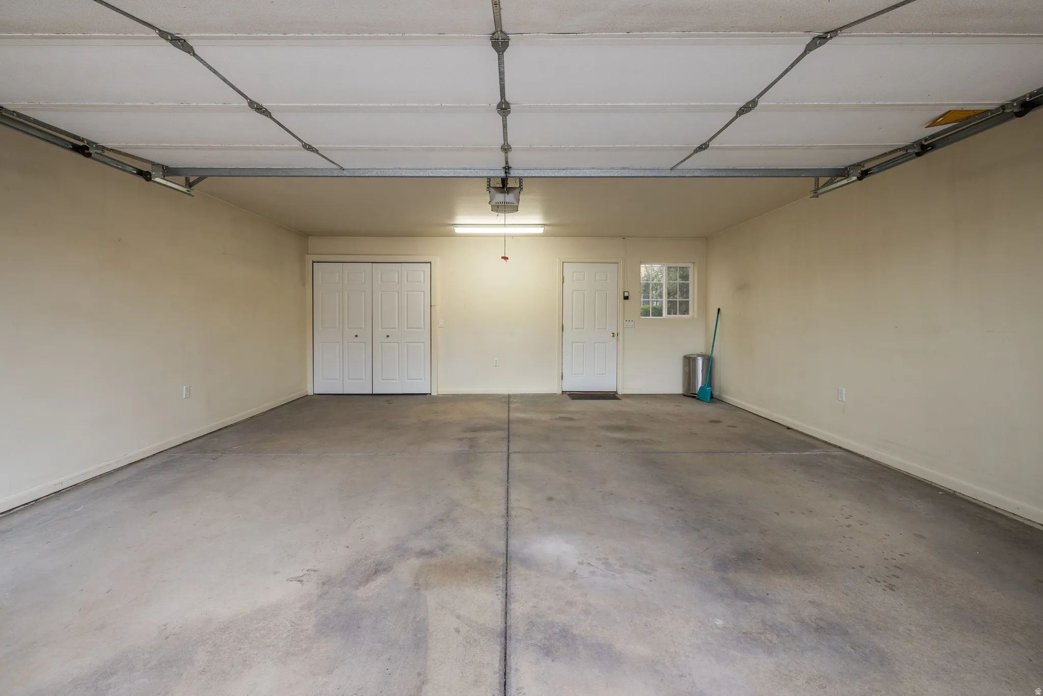 Concrete floor, overhead garage door system, interior door, window, bi-fold closet doors