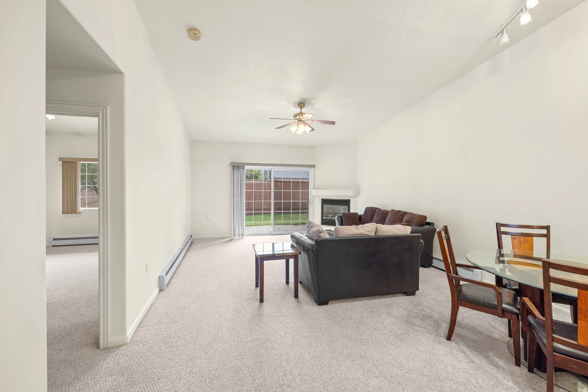 Open-concept living space with light-toned carpeting, a built-in fireplace, and a ceiling fan with integrated lighting