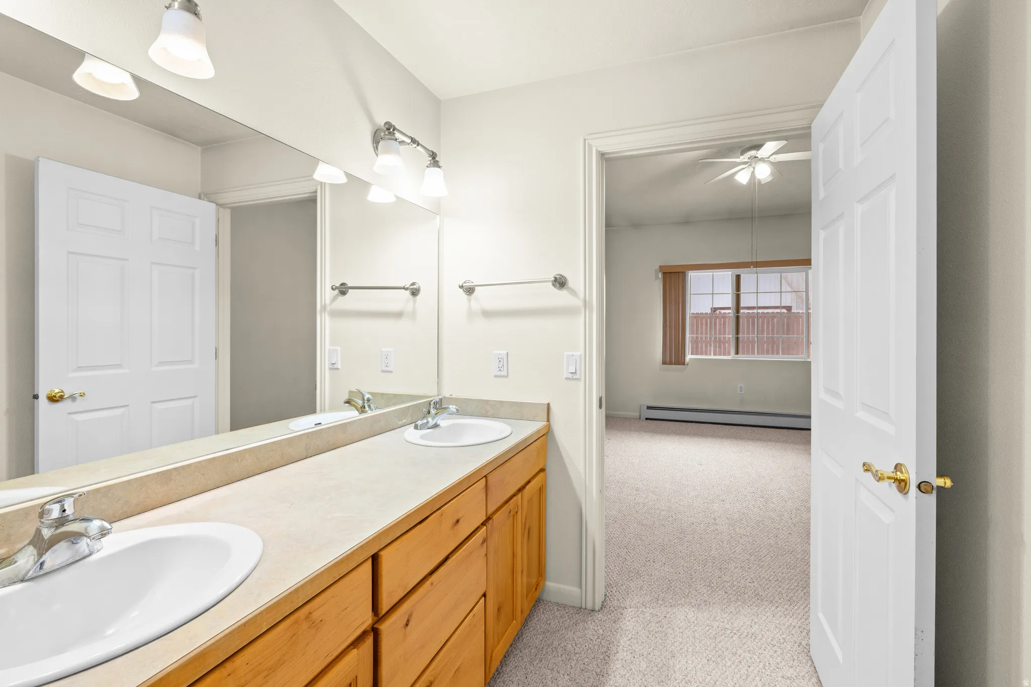 Dual vanity with integrated sinks, wood-finish cabinetry, and overhead sconce lighting