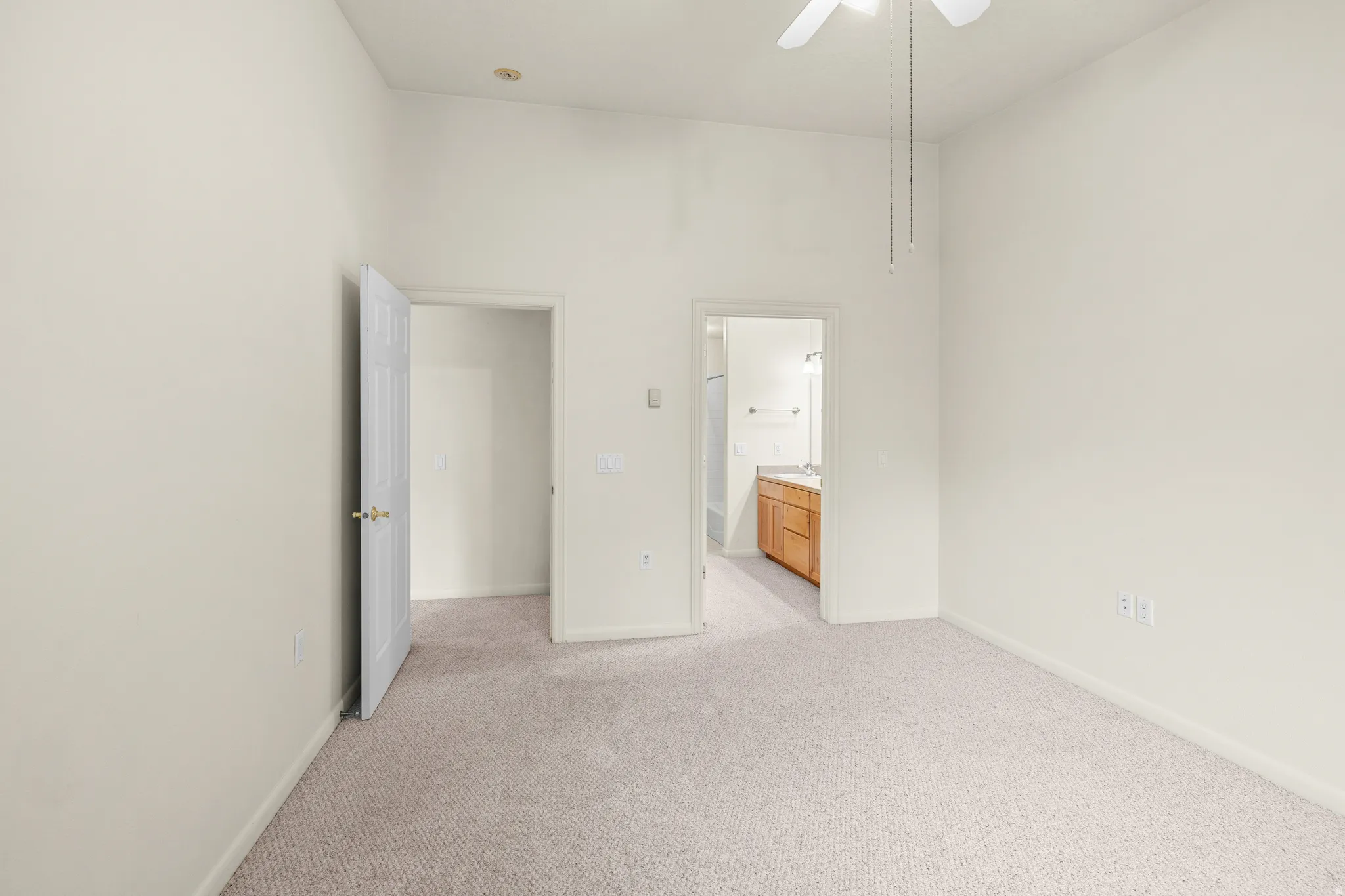 Vaulted ceiling with a ceiling fan, light-toned carpeting, and two interior doorways