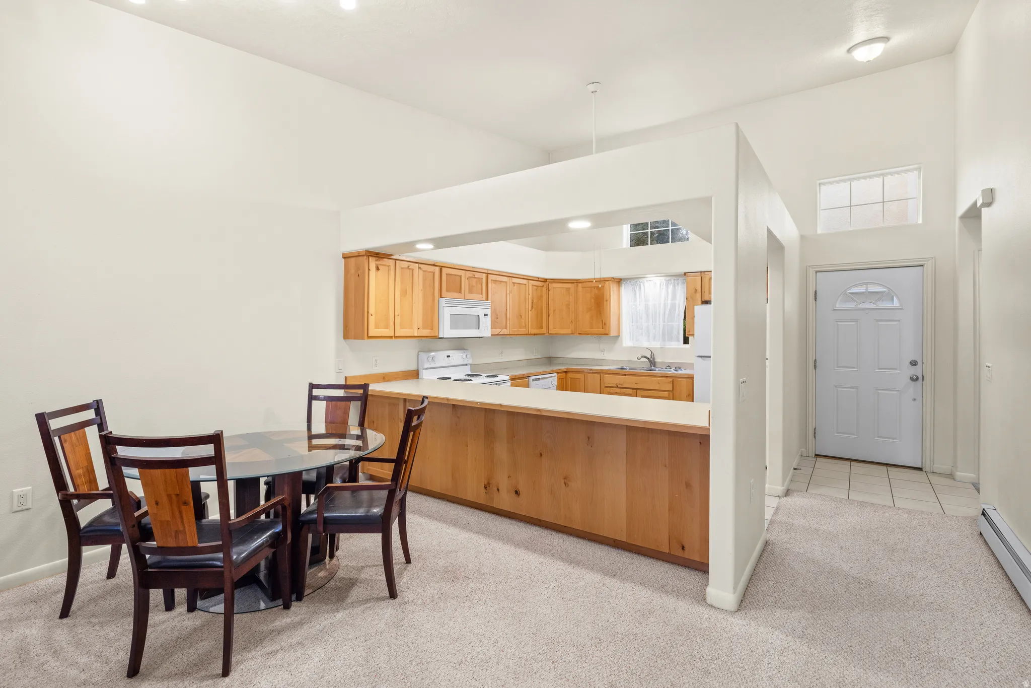 Kitchen with wood cabinetry, white appliances, and a breakfast bar