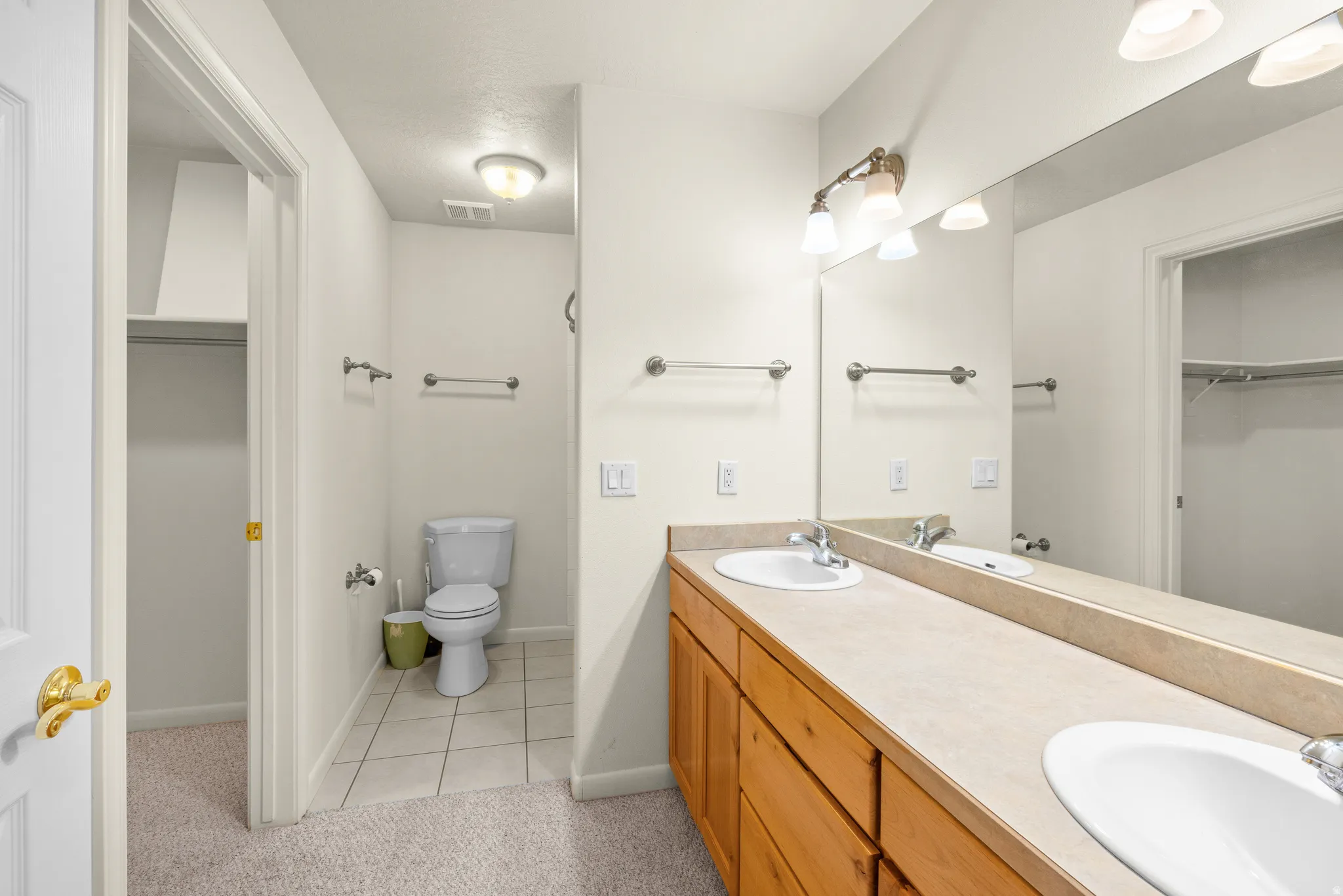 Double vanity featuring wood-finish cabinetry and integrated sinks, complemented by a large wall-mounted mirror