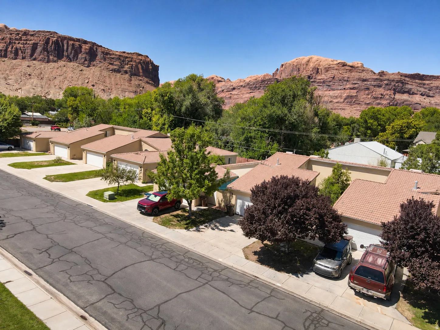 Multiple single-story properties featuring attached garages, paved driveways, and mature landscaping