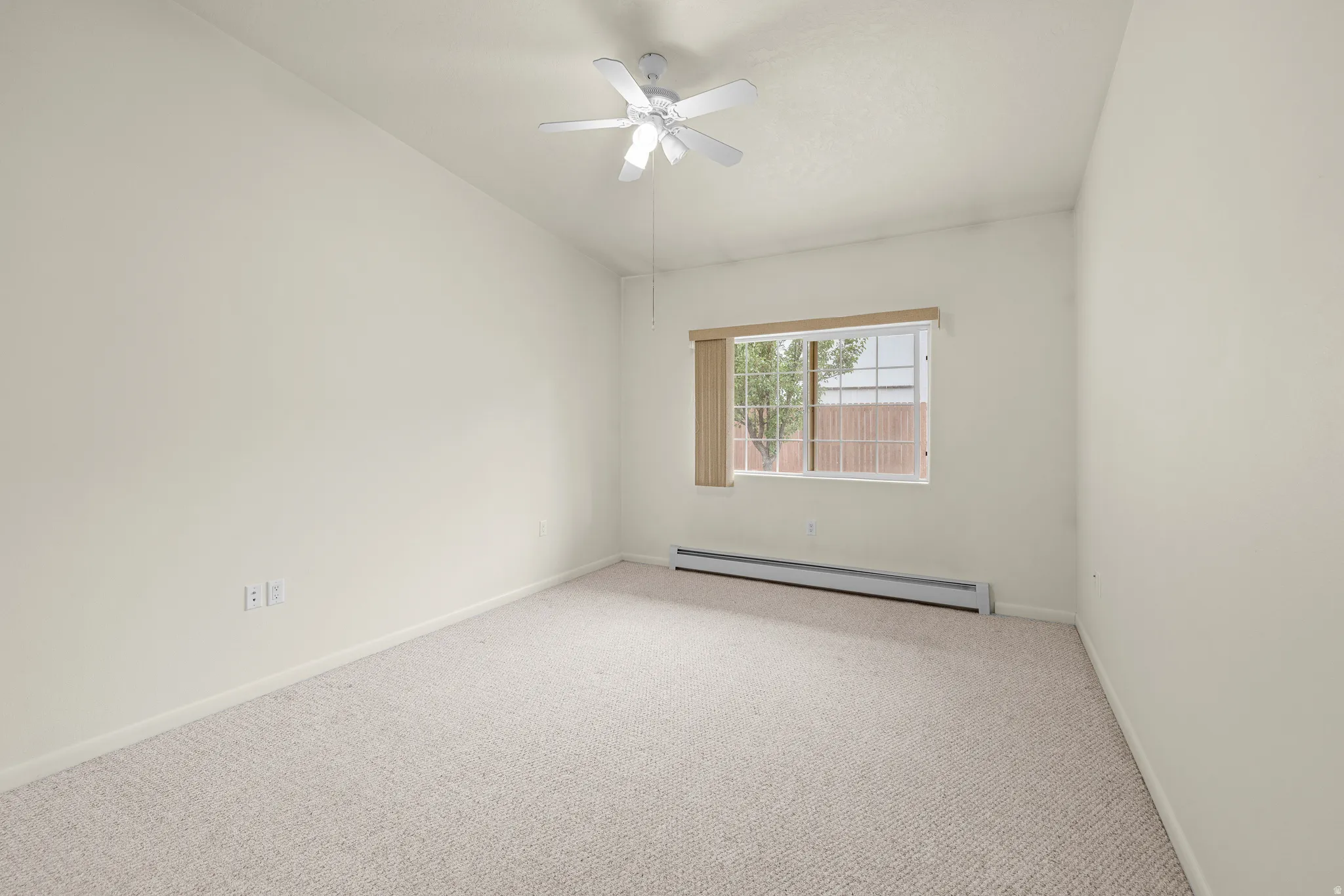Carpeted room featuring a window with vertical blinds, a ceiling fan, and baseboard heating