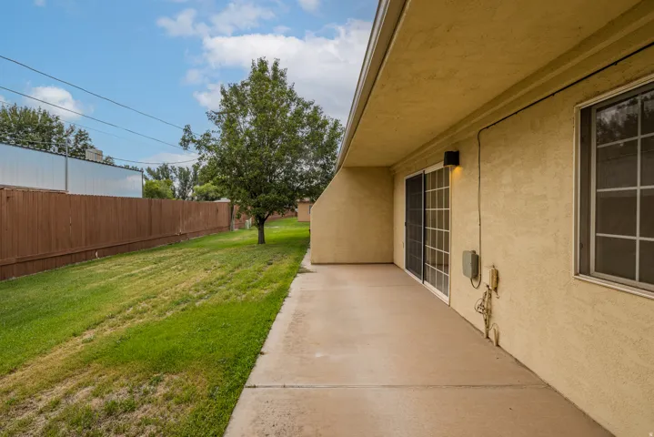 Exterior patio with a sliding glass door and an adjacent window, concrete flooring, and a stucco finish