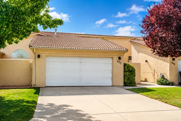 Stucco exterior featuring a two-car garage with a white door, a tile roof, and a semicircular transom window