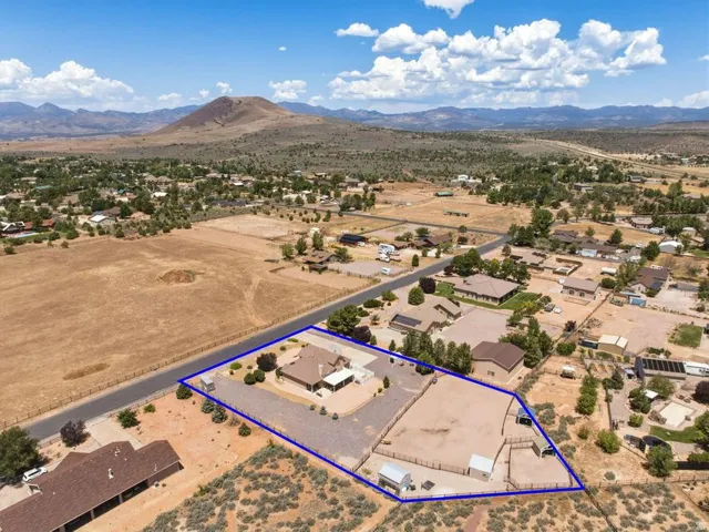Spacious property featuring a single-story residence, expansive cleared areas, a fenced corral, and auxiliary structures