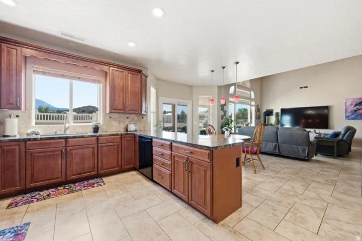Spacious kitchen featuring warm wood cabinetry, granite-style countertops, and a tile backsplash