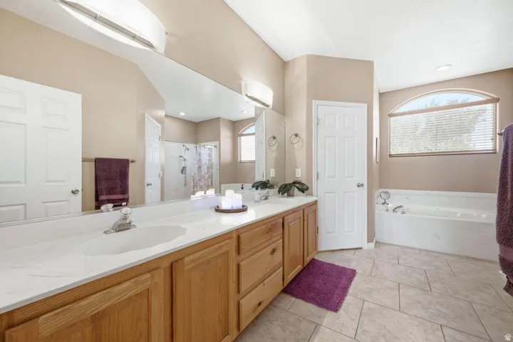 Dual vanity with built-in sinks, light wood cabinetry, and an expansive mirror