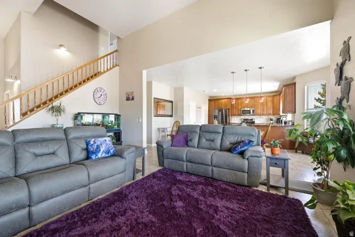 Open-concept living space featuring high ceilings, a prominent staircase with wood railing, and an expansive view of the kitchen area