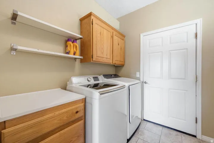 Dedicated utility space featuring light wood cabinetry, a light-toned countertop, and open shelving