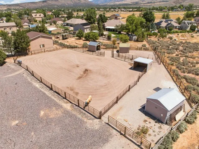 Expansive fenced equestrian arena featuring a sand surface, perimeter fencing, and an open-sided shelter