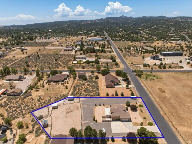 Expansive property featuring a tan stucco residence with an attached garage, paved driveway, and mature landscaping