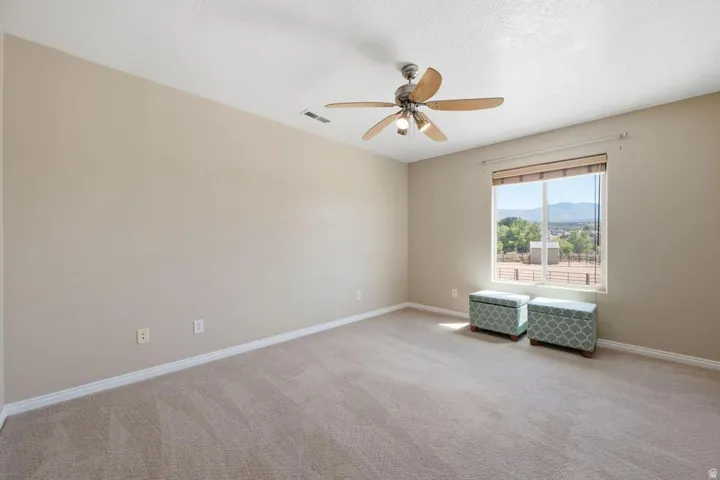 Carpeted room with a ceiling fan light fixture and a large window