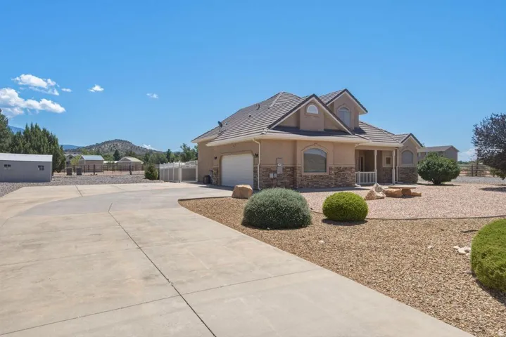 Stucco and stone facade home featuring a covered front porch, arched windows, and a concrete driveway