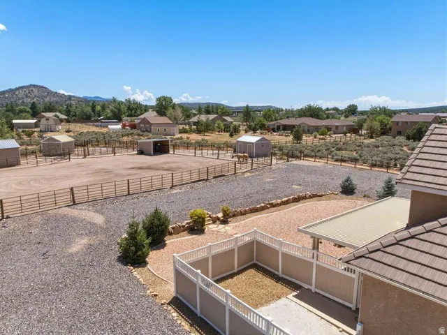 Expansive outdoor space featuring a large enclosed riding arena, multiple outbuildings, and a gravel-covered parking area