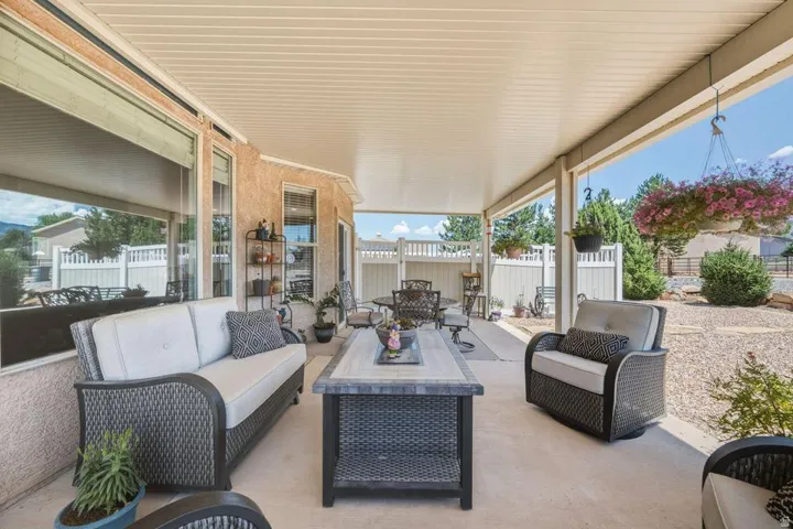 Spacious covered patio with concrete flooring, stucco exterior, and multiple windows