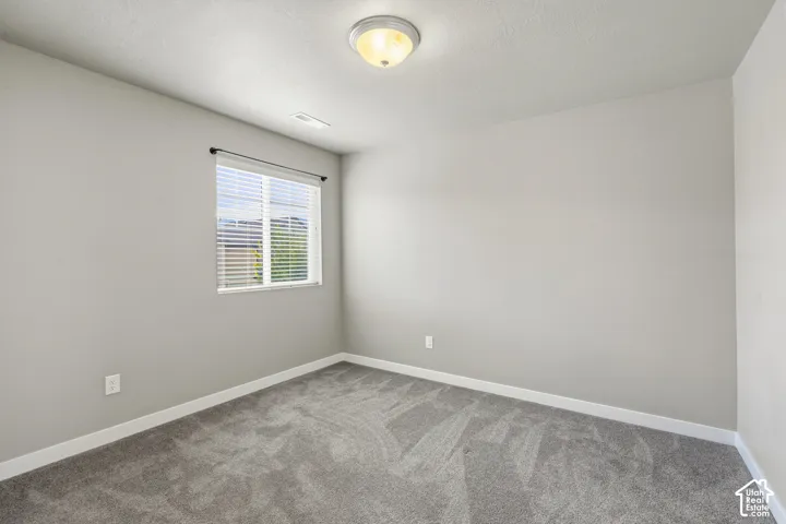 Neutral interior room featuring neutral wall paint, plush carpeting, a single-pane window with white horizontal blinds, and a semi-flush mount dome ceiling light