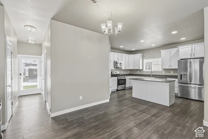 Kitchen featuring white cabinetry, center island with stone-finish countertop, wood-finish flooring, stainless steel appliances, and recessed lighting