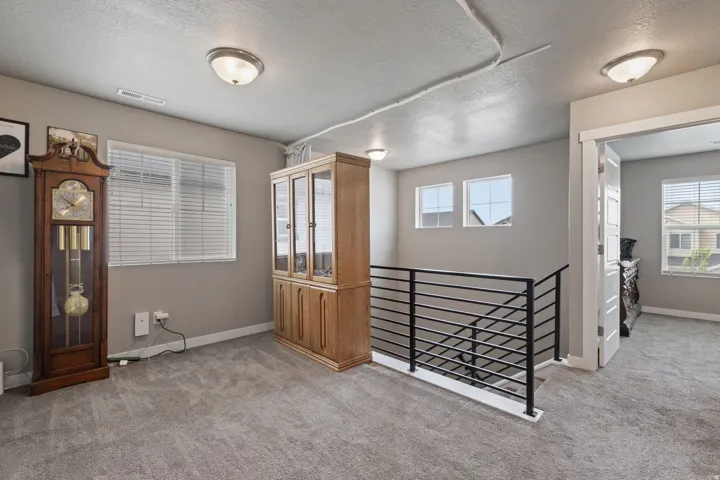 Carpeted landing area featuring a contemporary horizontal iron railing and a recessed lighting fixture