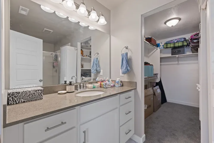 Bathroom vanity with an integrated sink, broad mirror, and built-in white cabinetry with drawers