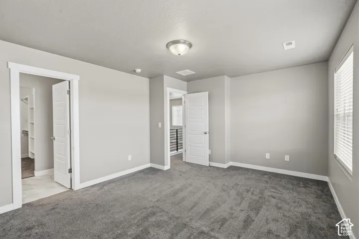Neutral-toned room featuring wall-to-wall carpeting, crisp white door trim, paneled doors, and a ceiling-mounted flush light fixture