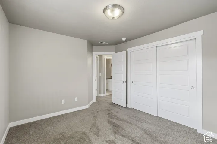 Neutral-toned interior featuring wall-to-wall carpeting, five-panel sliding closet doors, and a flush-mount overhead light fixture