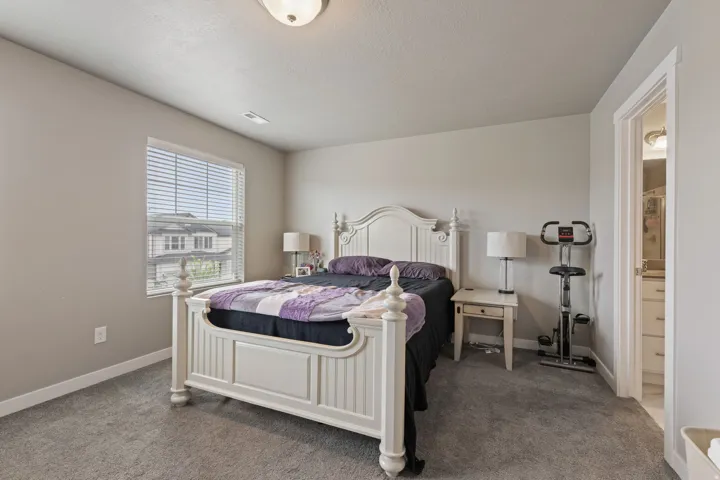Carpeted room with a ceiling-mounted light fixture and a window featuring blinds