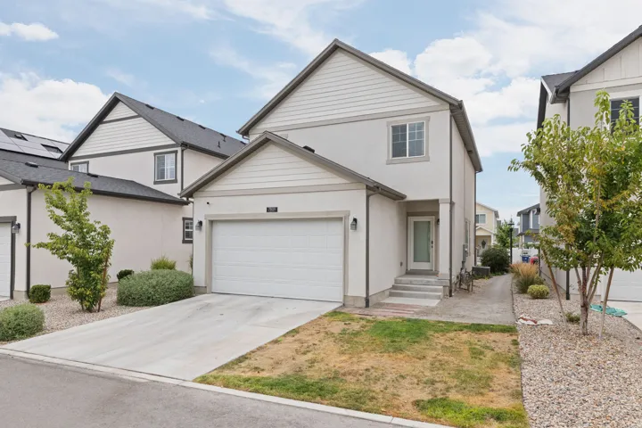 Two-story residence featuring a front-facing garage with a concrete driveway, a prominent entryway with steps, and a combination of stucco and siding exterior finishes