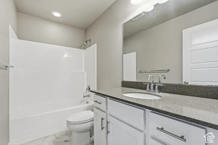 Bathroom featuring white cabinetry, solid surface countertop with an integrated basin, large vanity mirror, and a tub-shower combination with full-height surround